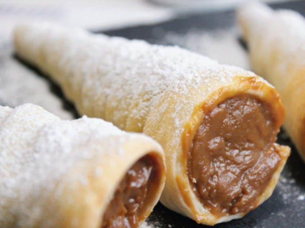 A small Peruvian dessert. Manjar blanco is filled into a shell of dough and dusted with powdered sugar. This dessert it called cachitos con manjar.