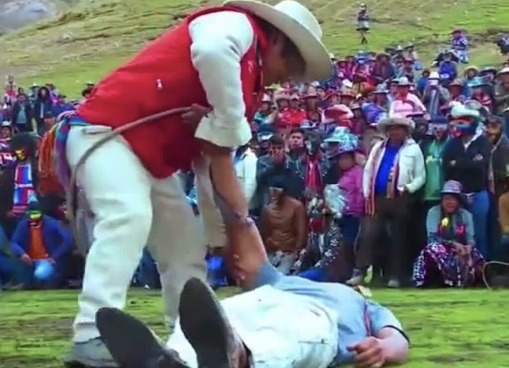 A referee helps a man to his feet after fighting during Takanakuy Peru.